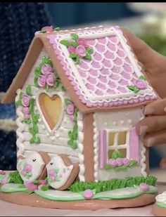 a person is decorating a small house with flowers and hearts on it's roof