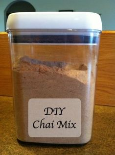 a container filled with dry chai mix on top of a wooden table next to a wall