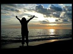 a person standing on the beach with their arms in the air