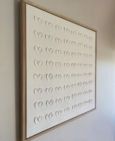 a white wall hanging on the side of a building with hearts cut out of it