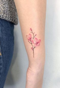 a small pink flower tattoo on the arm