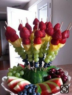 a bowl filled with fruit and skewers on top of a wooden table next to a door