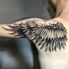 the back of a man's shoulder with an angel wing tattoo