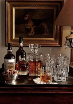 a table topped with bottles and glasses next to a painting