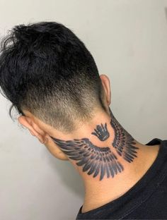 the back of a man's head with an eagle tattoo on his upper neck