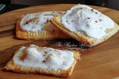 three pastries with white icing and cinnamon sprinkles on a cutting board