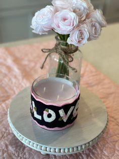 a vase with flowers in it sitting on a table next to a lit candle holder