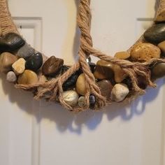 a wreath made out of rope with rocks on it hanging from the front door handle