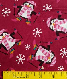 a ruler is next to a red fabric with snowflakes and penguins on it