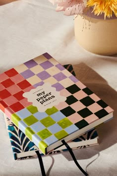 a colorful book sitting on top of a table next to a vase with flowers in it