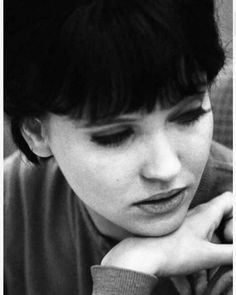 a black and white photo of a woman with her hand on her chin looking down