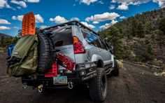 an suv parked on the side of a dirt road with luggage strapped to it's back