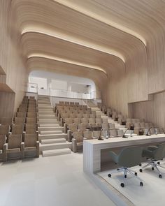 an empty lecture hall with rows of chairs and desks in the center, along with stairs leading up to the second floor