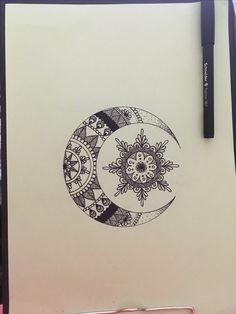 a pen and ink drawing of a crescent moon with flowers on the side, sitting on top of a piece of paper