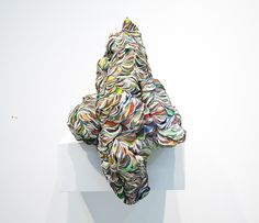 an abstract sculpture is displayed on a white pedestal