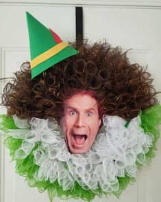 a man with curly hair wearing a green and white wreath on his head is making a funny face