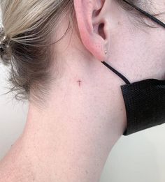 a woman with a small cross tattoo on her left side behind the ear, wearing a black choker