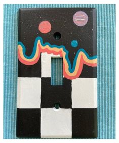 a black and white checkerboard light switch cover with colorful designs on the side