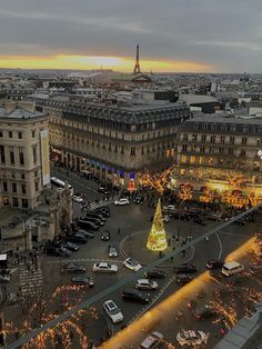 an aerial view of a christmas tree in the middle of a busy city street at dusk