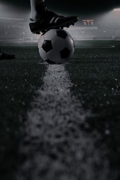 a soccer ball sitting on top of a field next to a person's feet