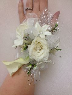 a woman's hand holding a bouquet of white flowers and pearls on her wrist