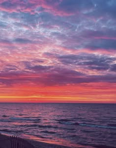 the sun is setting over the ocean with pink and purple clouds