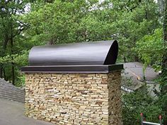 a brick oven sitting on the side of a road in front of trees and bushes