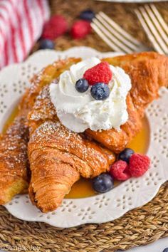 croissants topped with whipped cream and berries on a white plate