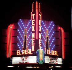 a theater marquee lit up at night with neon lights on the front and sides