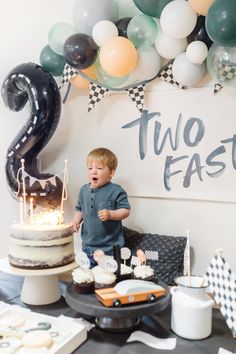 a young boy standing in front of a birthday cake