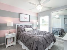 a bedroom with pink, gray and white stripes on the walls is pictured in this image