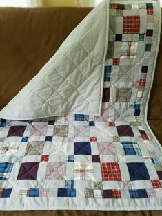 a quilted blanket sitting on top of a couch next to a brown sofa cushion