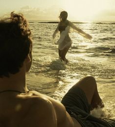 two people in the water with one person laying on his back and another standing up