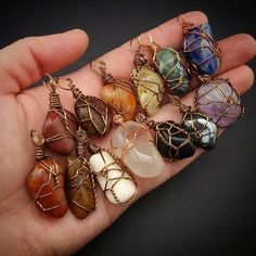 a person is holding several different colored stones in their hand and wire wrapped around them