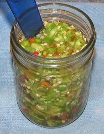 a glass jar filled with food sitting on top of a blue table cloth next to a wooden spoon