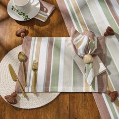 a place setting on a wooden table with plates and utensils, napkins and cups