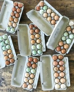 several trays filled with eggs sitting on top of a wooden table next to each other