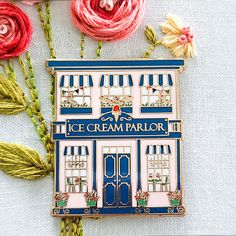 an ice cream parlor pin sitting on top of a table next to flowers and yarn