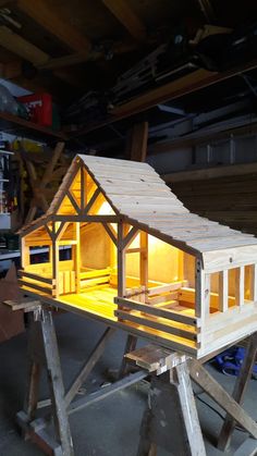 a small wooden house sitting on top of a workbench in a garage next to tools