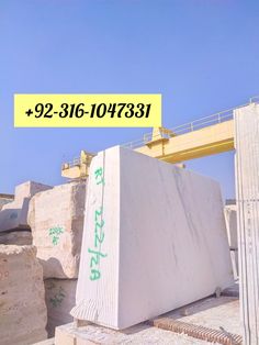 a large piece of white marble sitting on top of a pile of cement blocks in front of a yellow crane