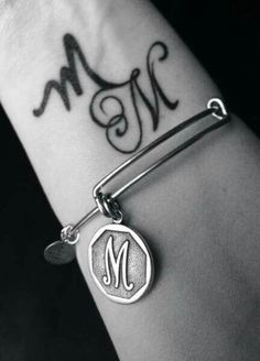 a person with a tattoo on their arm and the word m is written in black ink