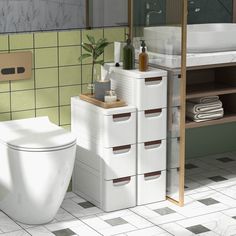 a white toilet sitting next to a sink in a green and white tiled bathroom area