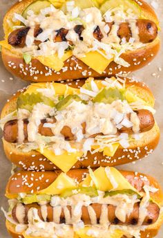 three hot dogs covered in cheese and toppings