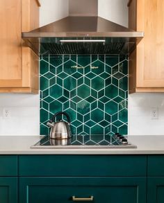 a teal kitchen with green tile backsplash and stainless steel range hood over the stove