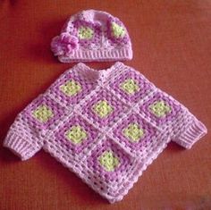 a crocheted baby sweater and hat on a table