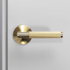 a close up of a metal door handle on a white and silver door with gold trim