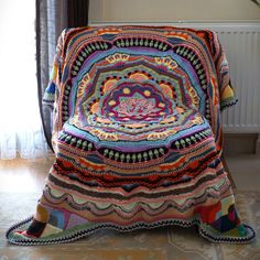 a crocheted blanket sitting on top of a chair in front of a window