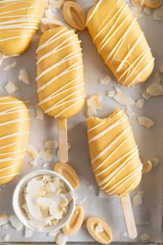 several popsicles on a baking sheet with white icing and some other toppings