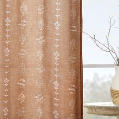 a vase sitting next to a curtain on a window sill