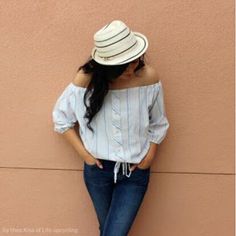 a woman leaning against a wall with her back to the camera, wearing jeans and a hat